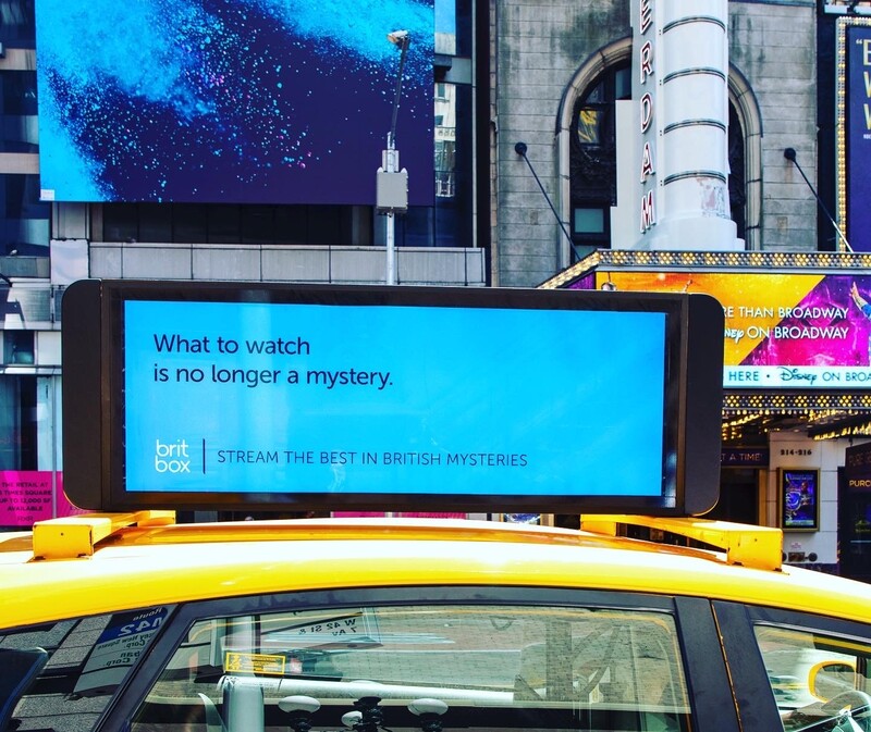 NYC taxi rooftop screen showing BritBox 'What to watch is no longer a mystery' ad, Times Square