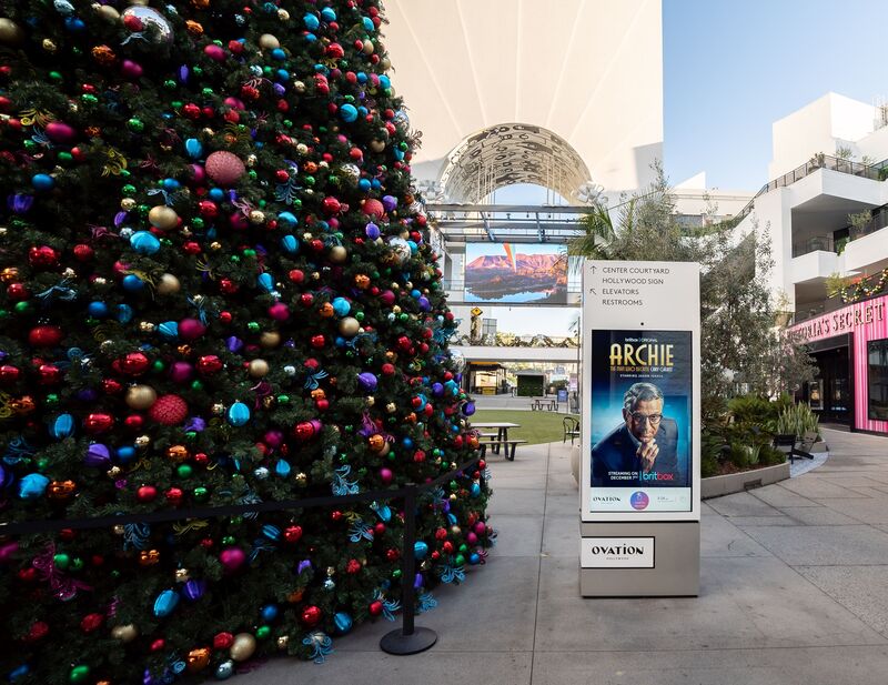 BritBox 'Archie' digital kiosk at Ovation Hollywood outdoor courtyard with Christmas tree