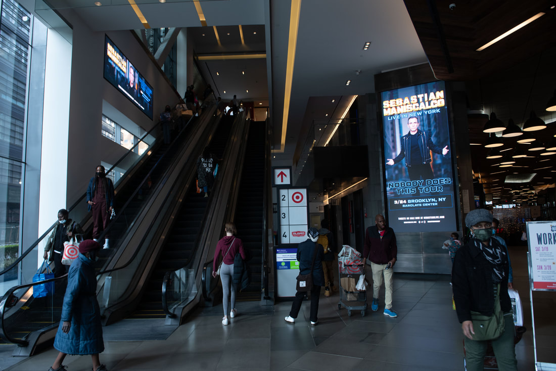 Sebastian Maniscalco vertical digital kiosk in Brooklyn Center mall atrium near escalators