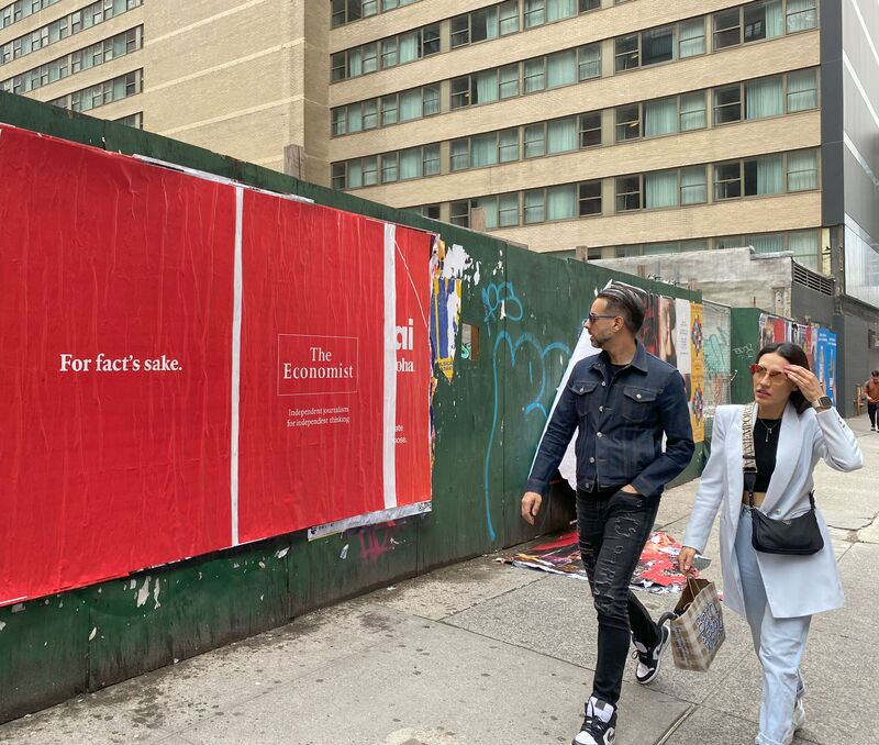 The Economist 'For fact's sake.' construction hoarding wall posters, NYC, two pedestrians walking by