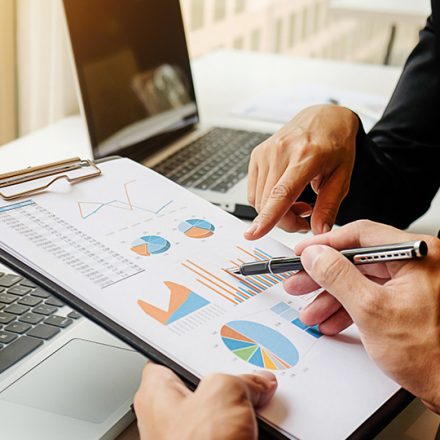 Two people reviewing colorful charts and graphs