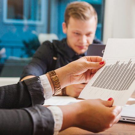 Woman holding a bar-chart document while a colleague reviews it