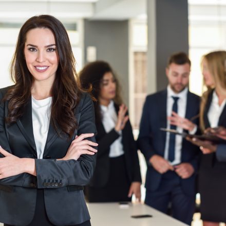 Confident businesswoman with her team in the background