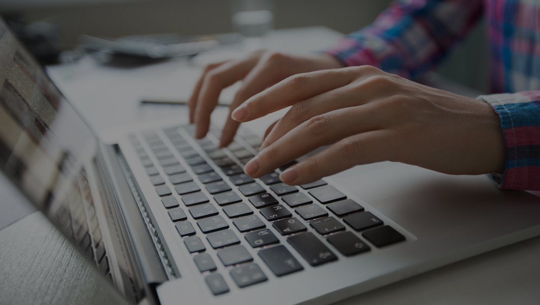 Hands typing on a laptop keyboard in a modern office