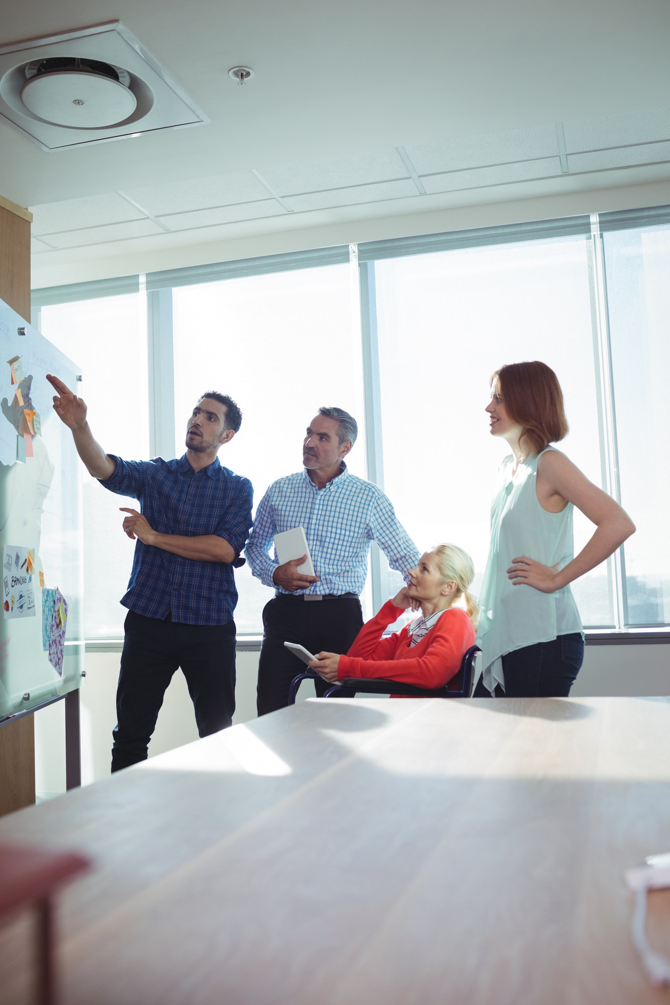 Four colleagues discussing ideas at a whiteboard with sticky notes