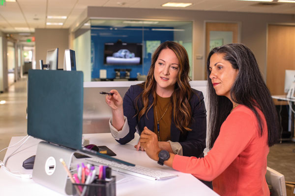 Two women collaborating at a desk in a modern office