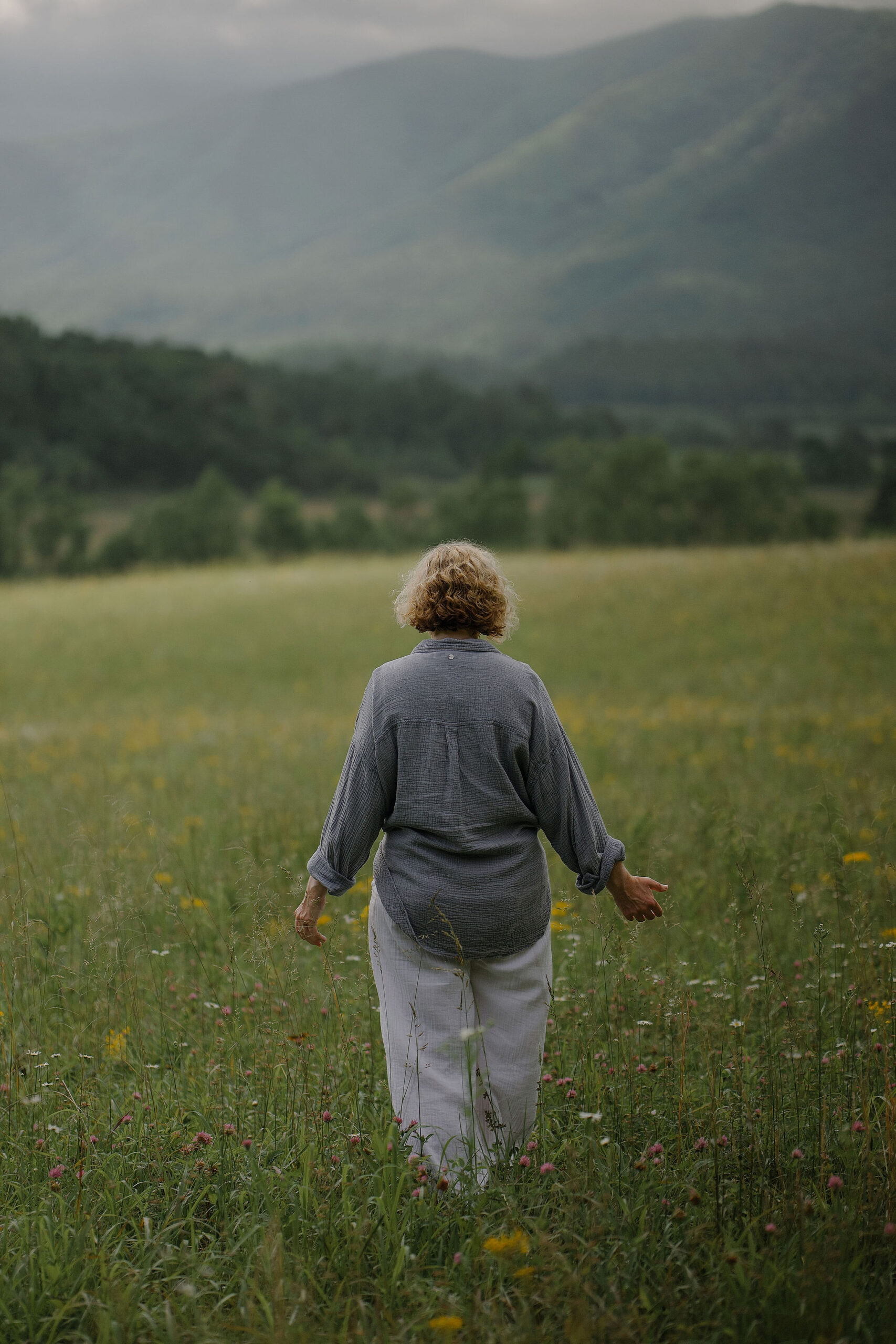 Booth Andrews walking through a wildflower meadow toward misty mountains