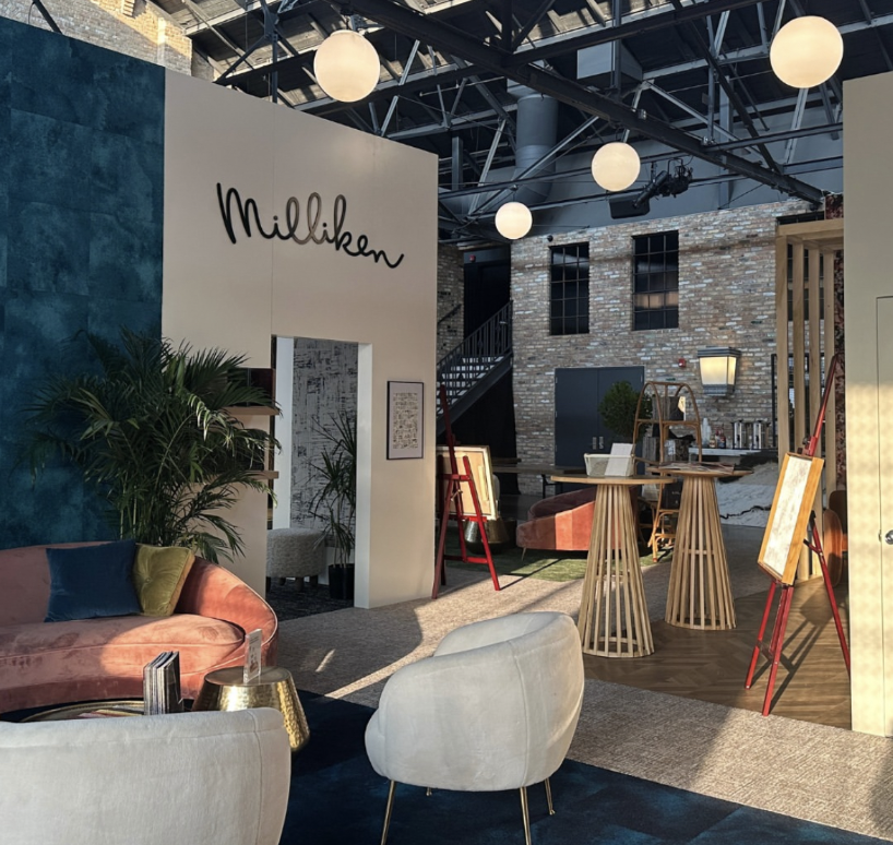 Milliken booth interior with pink velvet sofa, rattan tables and globe pendant lights