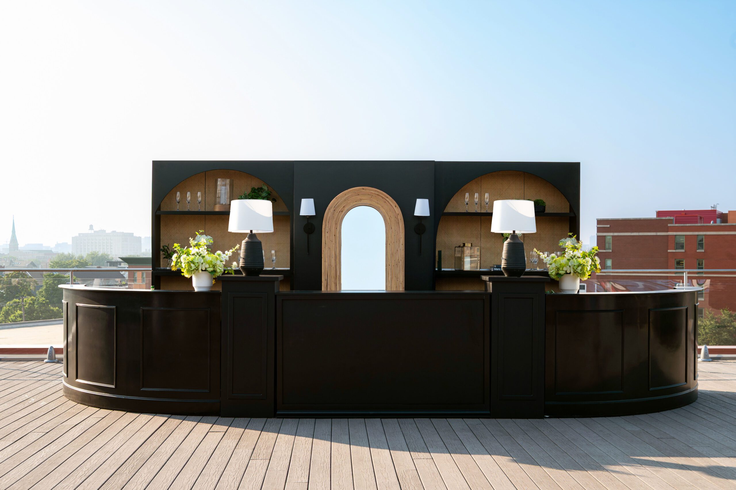 Stylish curved black bar unit with arch detailing on a rooftop deck overlooking the Chicago skyline