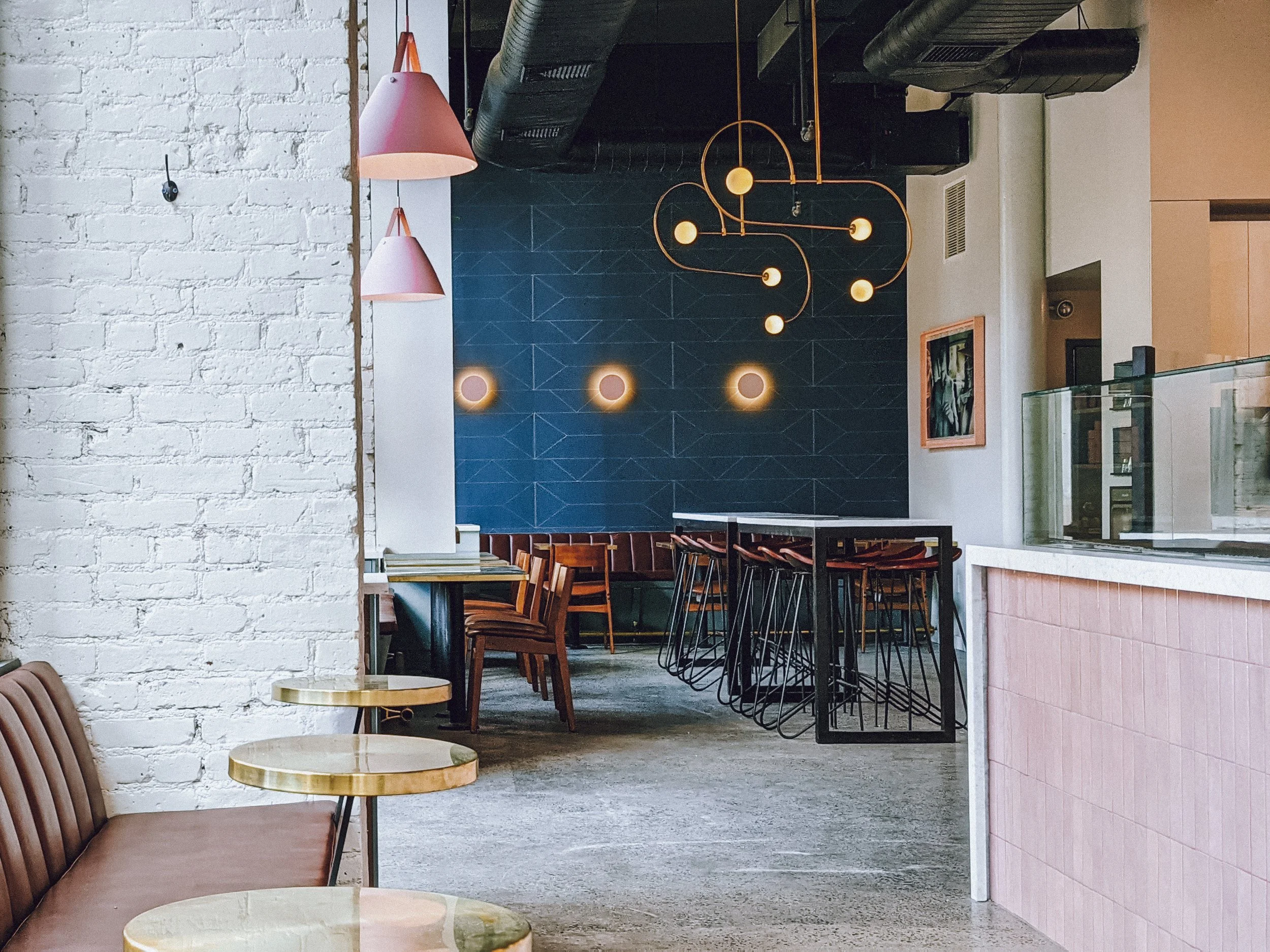 Butler interior with white brick, pink pendant lamps, blue tiled wall and pink-tiled ordering counter