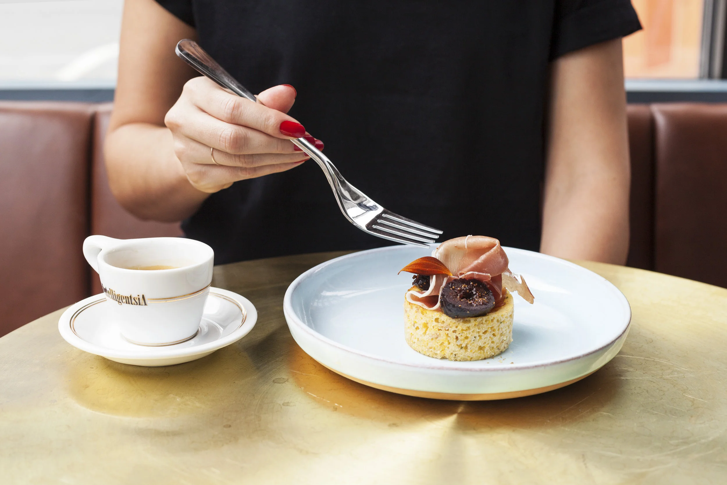 A fork reaching toward a savoury ham-and-fig muffin beside an Intelligentsia espresso cup