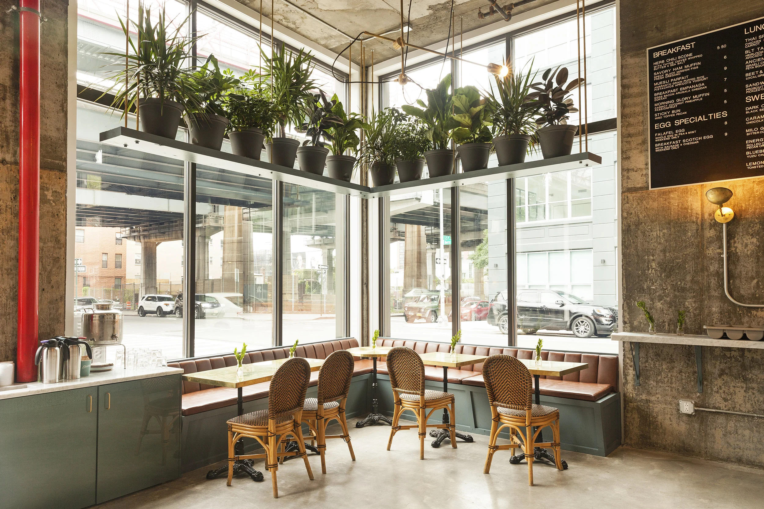 Butler corner with hanging potted plants, rattan chairs, banquette booths and a menu board