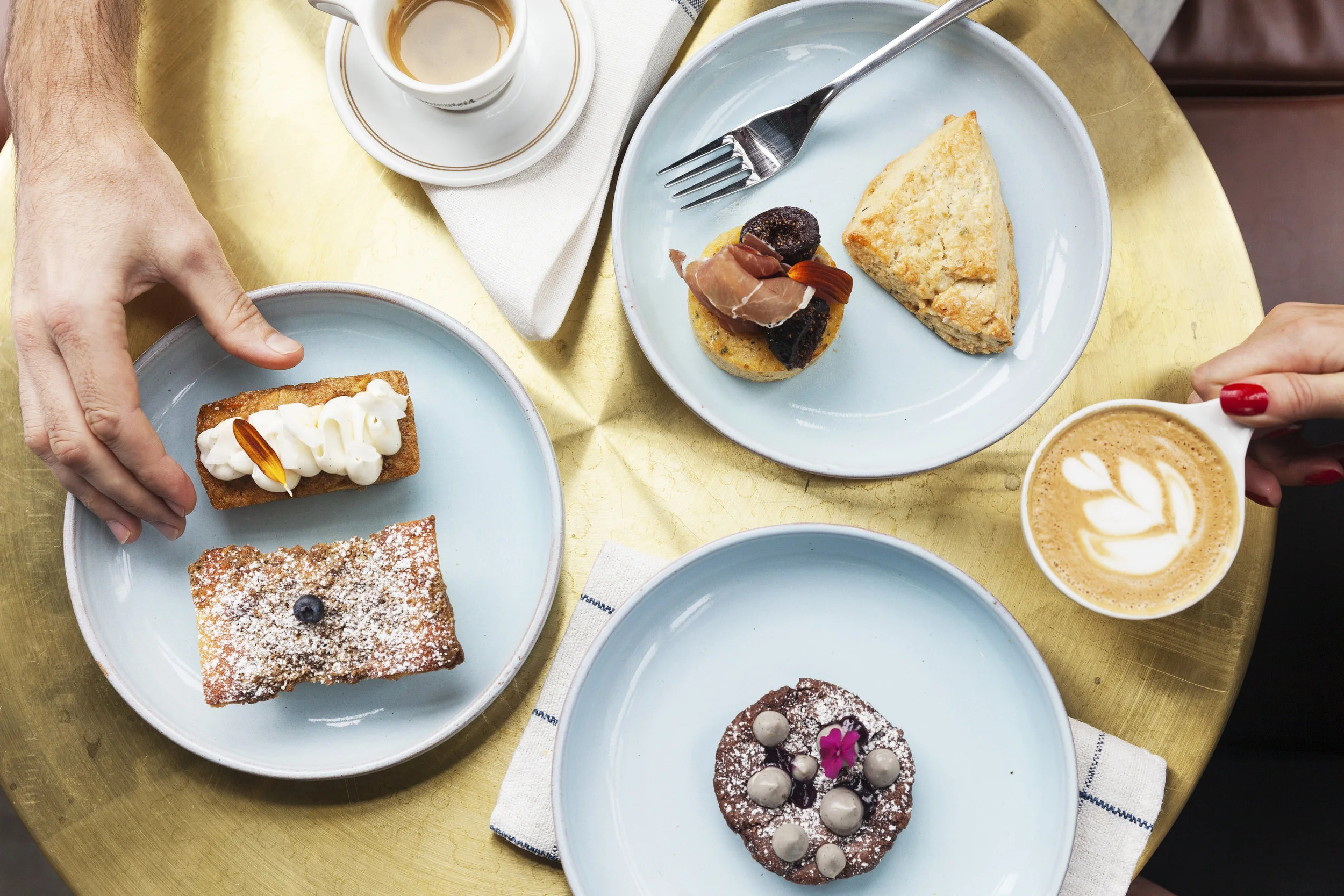Overhead pastry spread — babka, scone and chocolate brownie tart — with espresso and latte