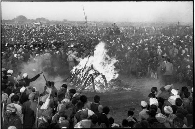 Black-and-white photograph by Henri Cartier-Bresson of Gandhi's cremation on the banks of the Jumna River, India, 1948: an enormous crowd surrounding a burning funeral pyre.