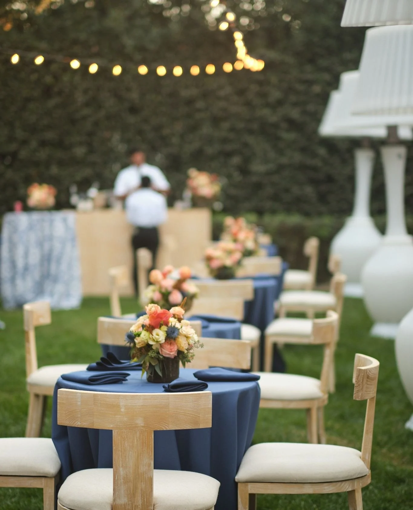 Outdoor garden dinner with navy linens and string lights at dusk