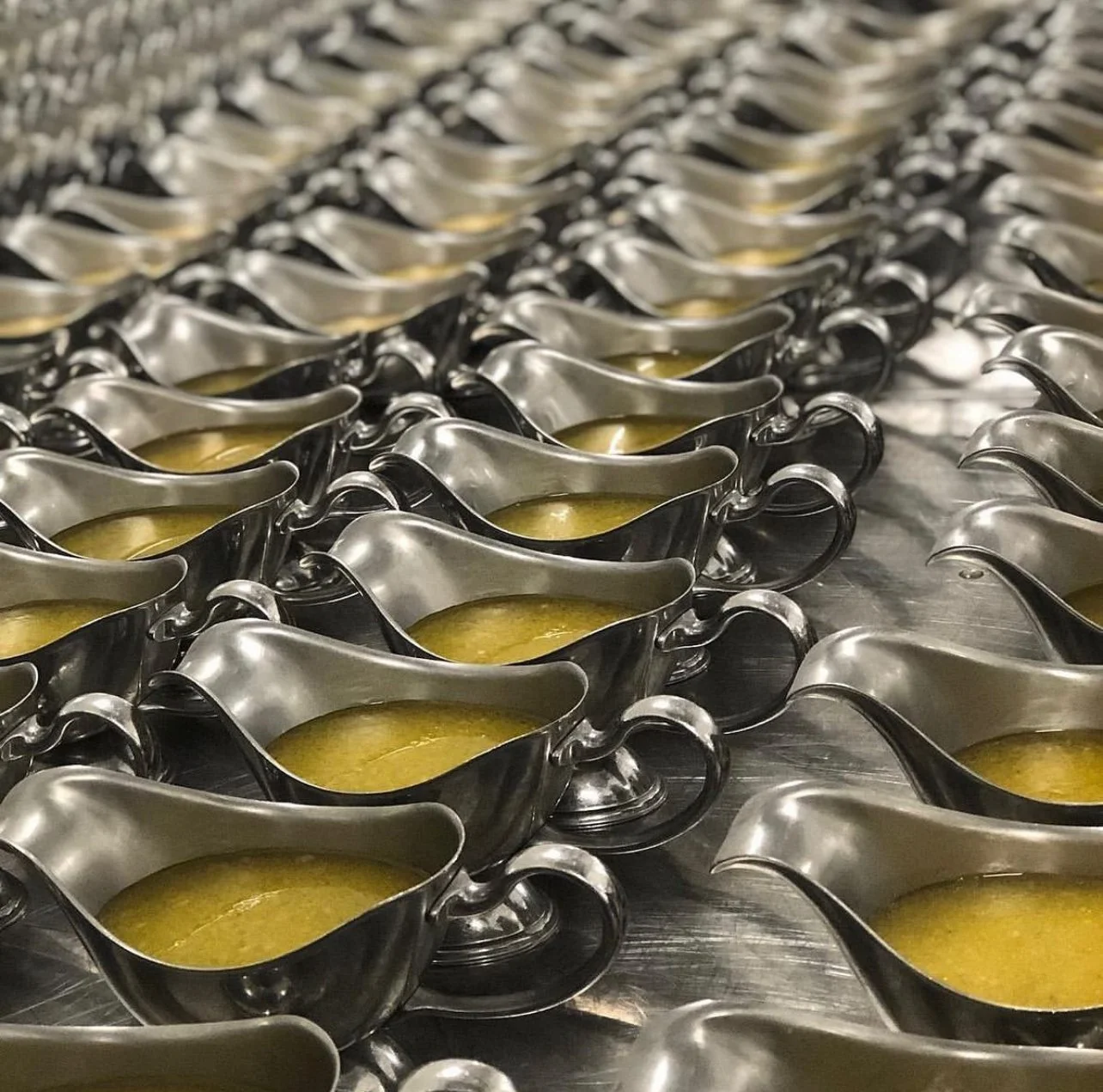 Rows of silver gravy boats filled with golden sauce