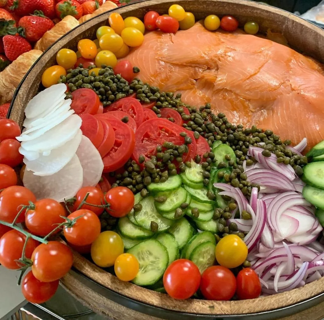 Wooden bowl of smoked salmon with capers, tomato and onion