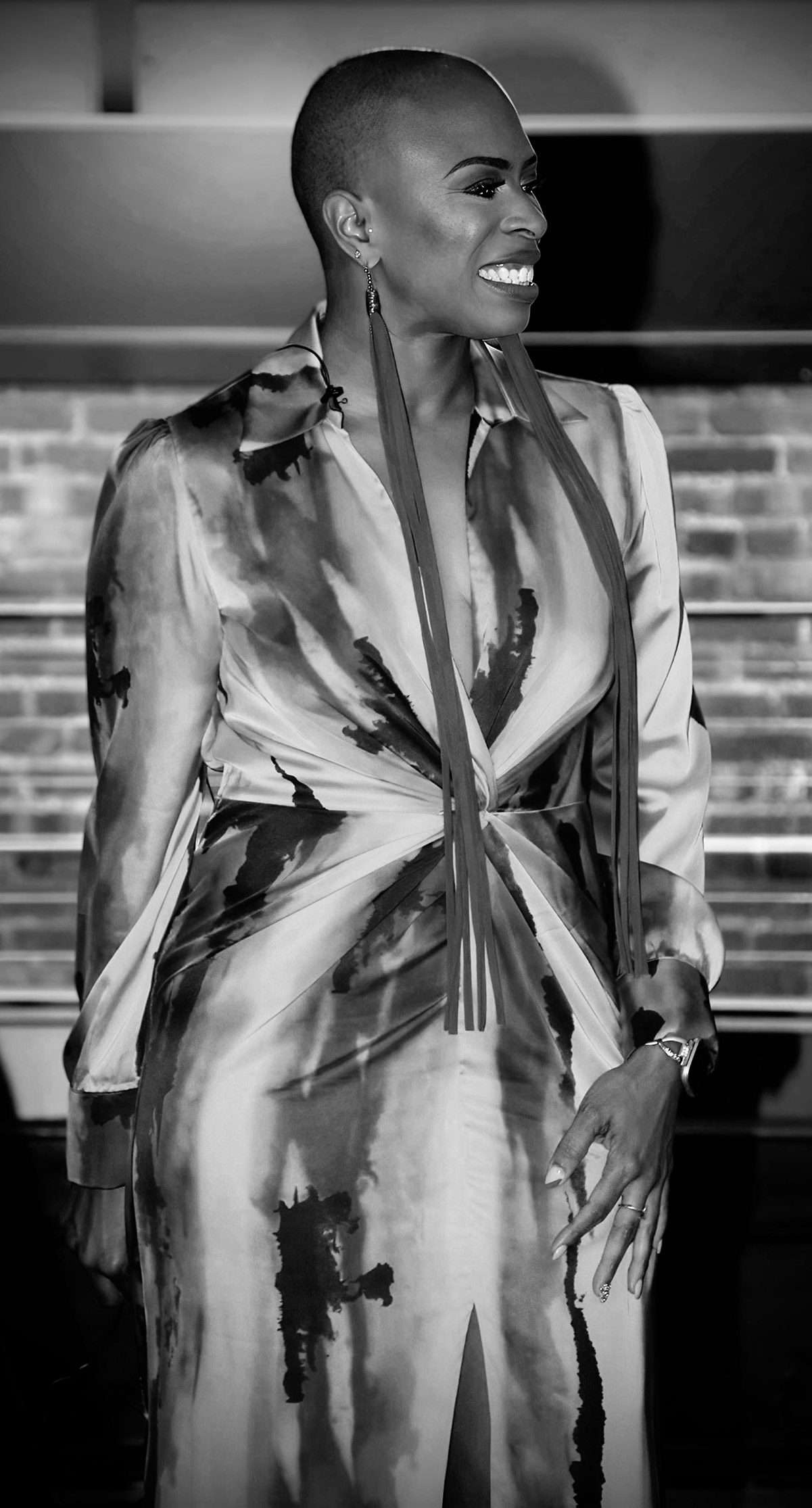Black-and-white portrait of a smiling founder of Charlton●Charlton & Associates in a patterned satin dress with long tassel earrings