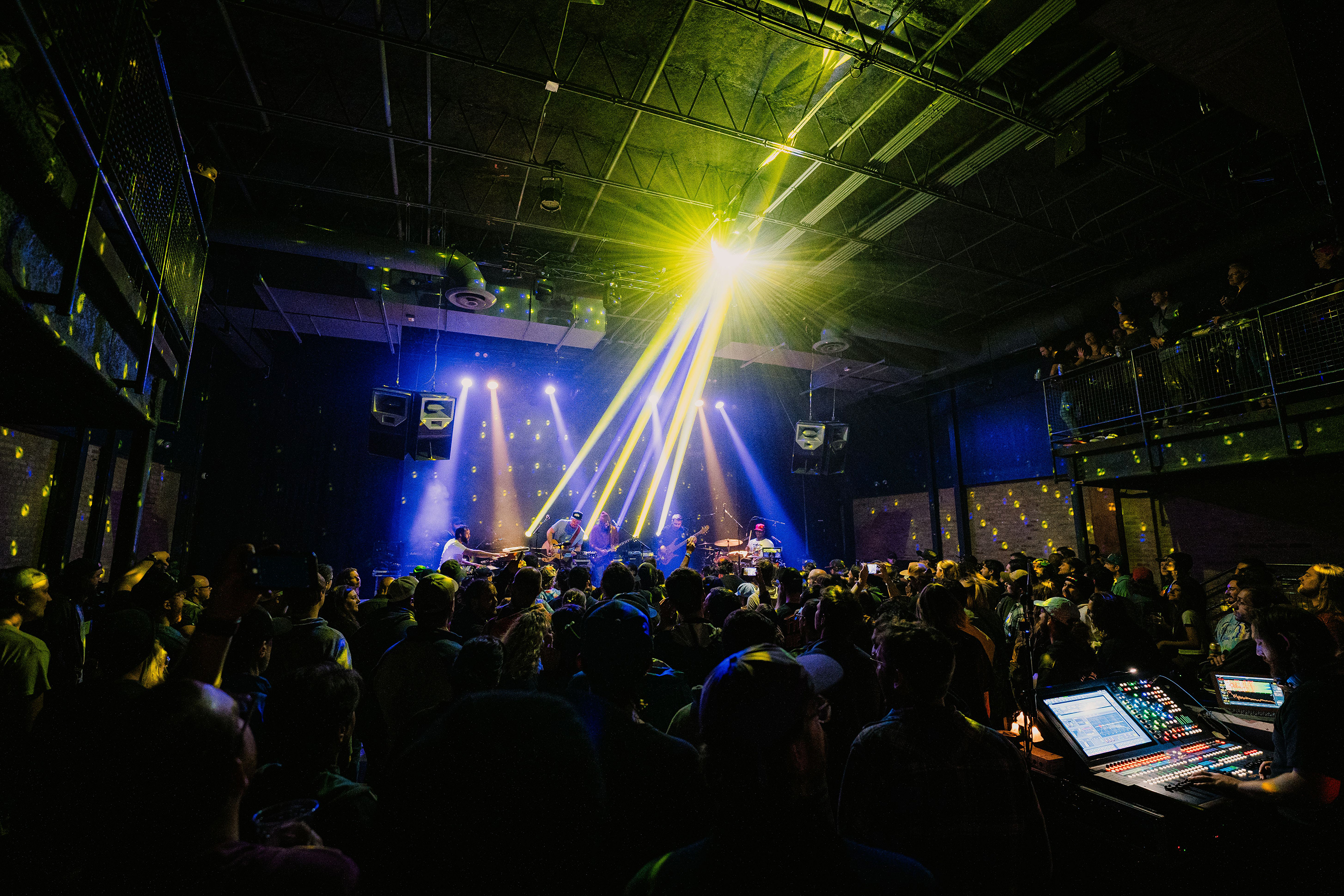 Chop Shop concert venue interior during a live show with dramatic yellow and blue laser beams over a packed crowd