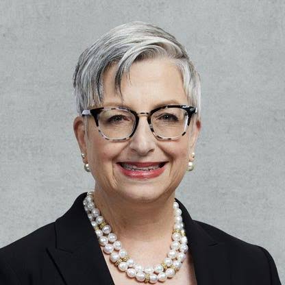 Carol Tome, older woman with short grey hair, glasses and a pearl necklace