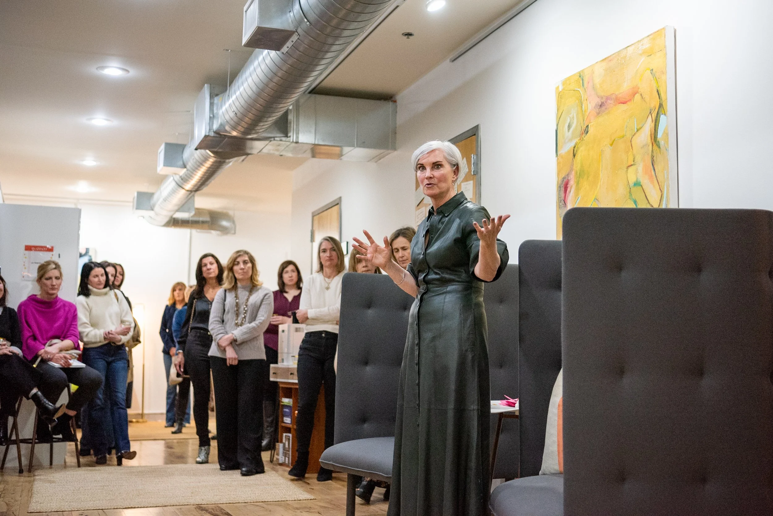Christina Langdon speaking and gesturing to a room full of women at her book launch