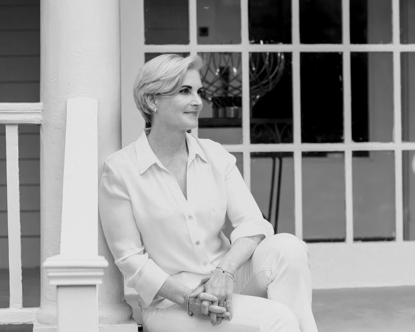 Christina Langdon seated on a porch step in a white blouse, black and white portrait
