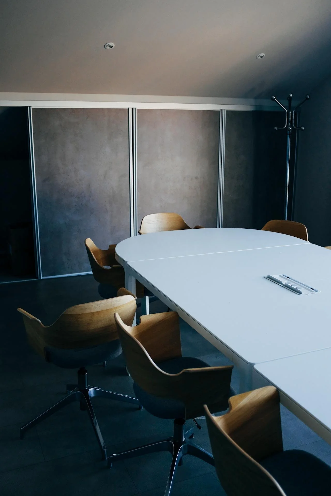 Empty boardroom with a long table and wooden chairs in moody light