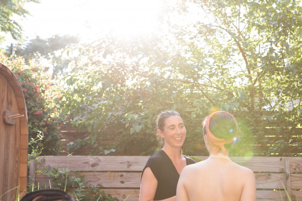 Liz smiling in the garden by the barrel sauna in golden sunlight