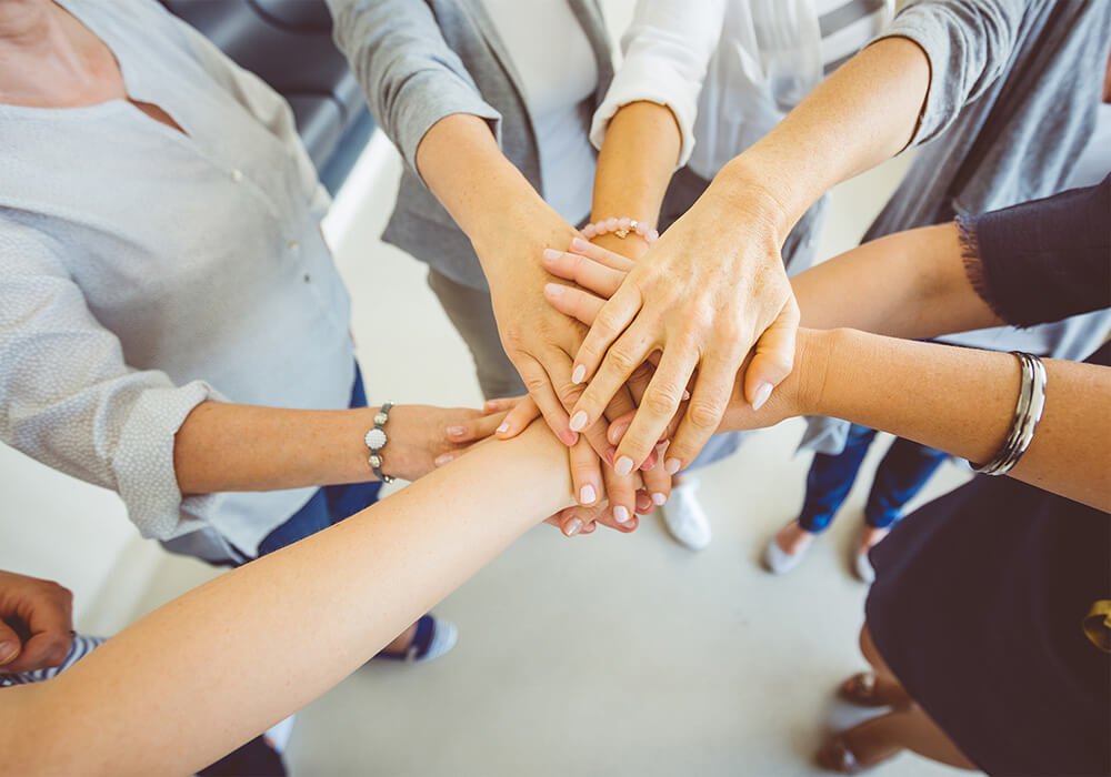 Aerial close-up of a group of colleagues stacking their hands together in a teamwork gesture