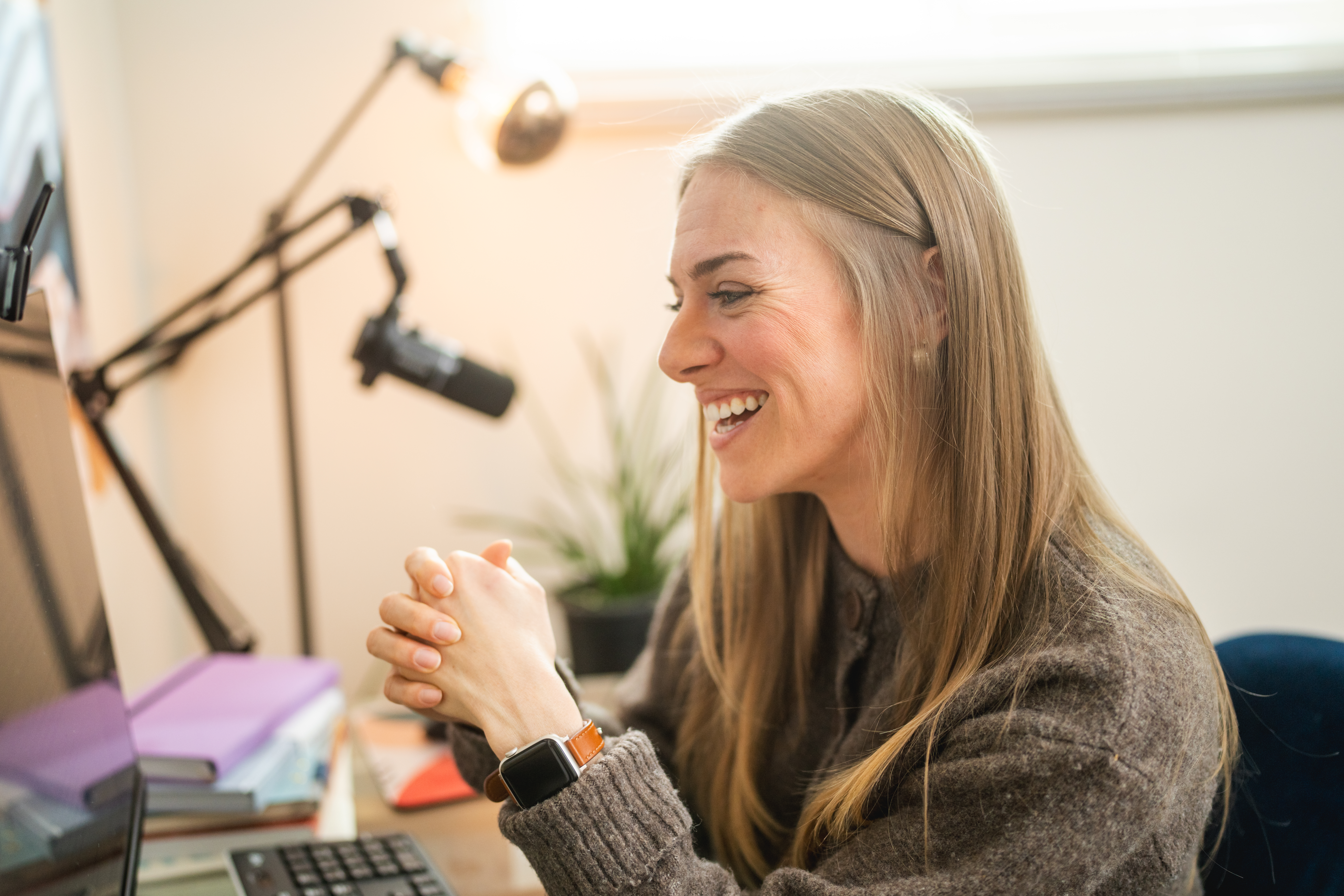 Smiling woman laughing at her home-office desk during a coaching session