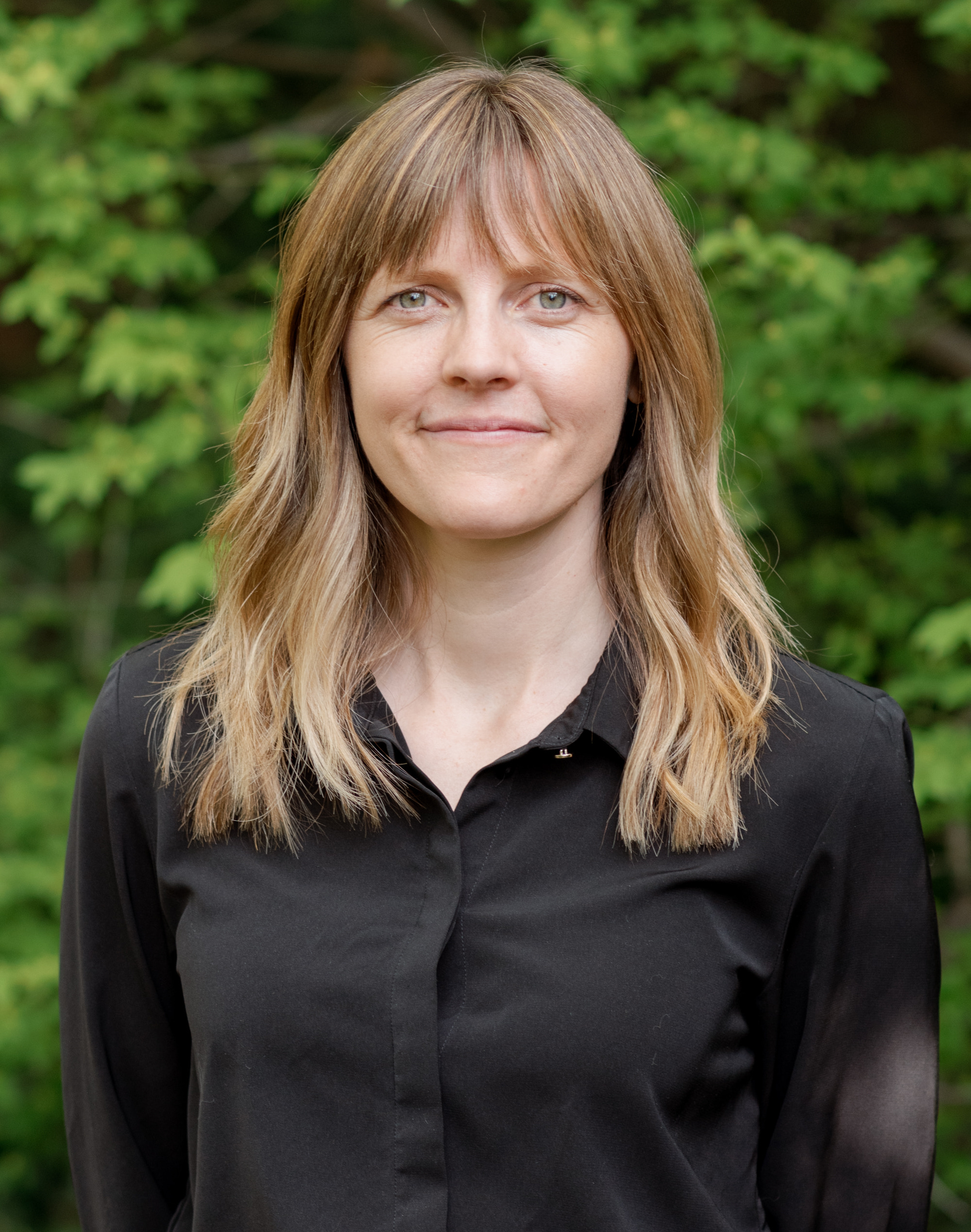May, Master Certified Coach, outdoor portrait against green foliage