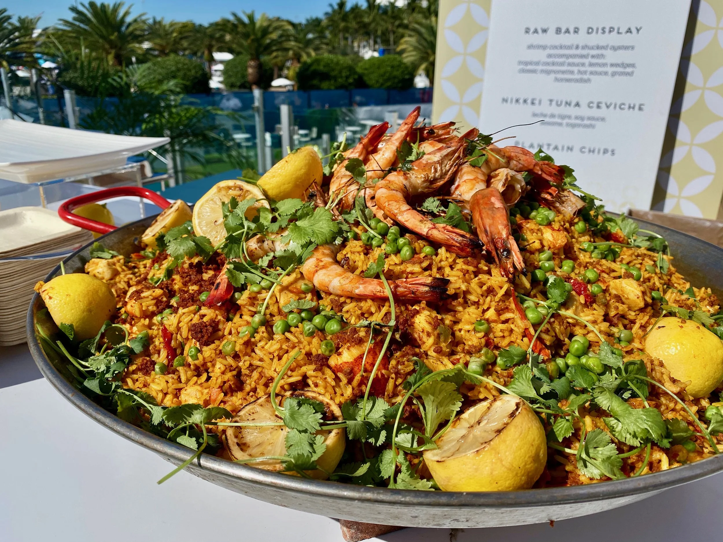 Large paella pan with shrimp, rice, peas and cilantro at an outdoor culinary event