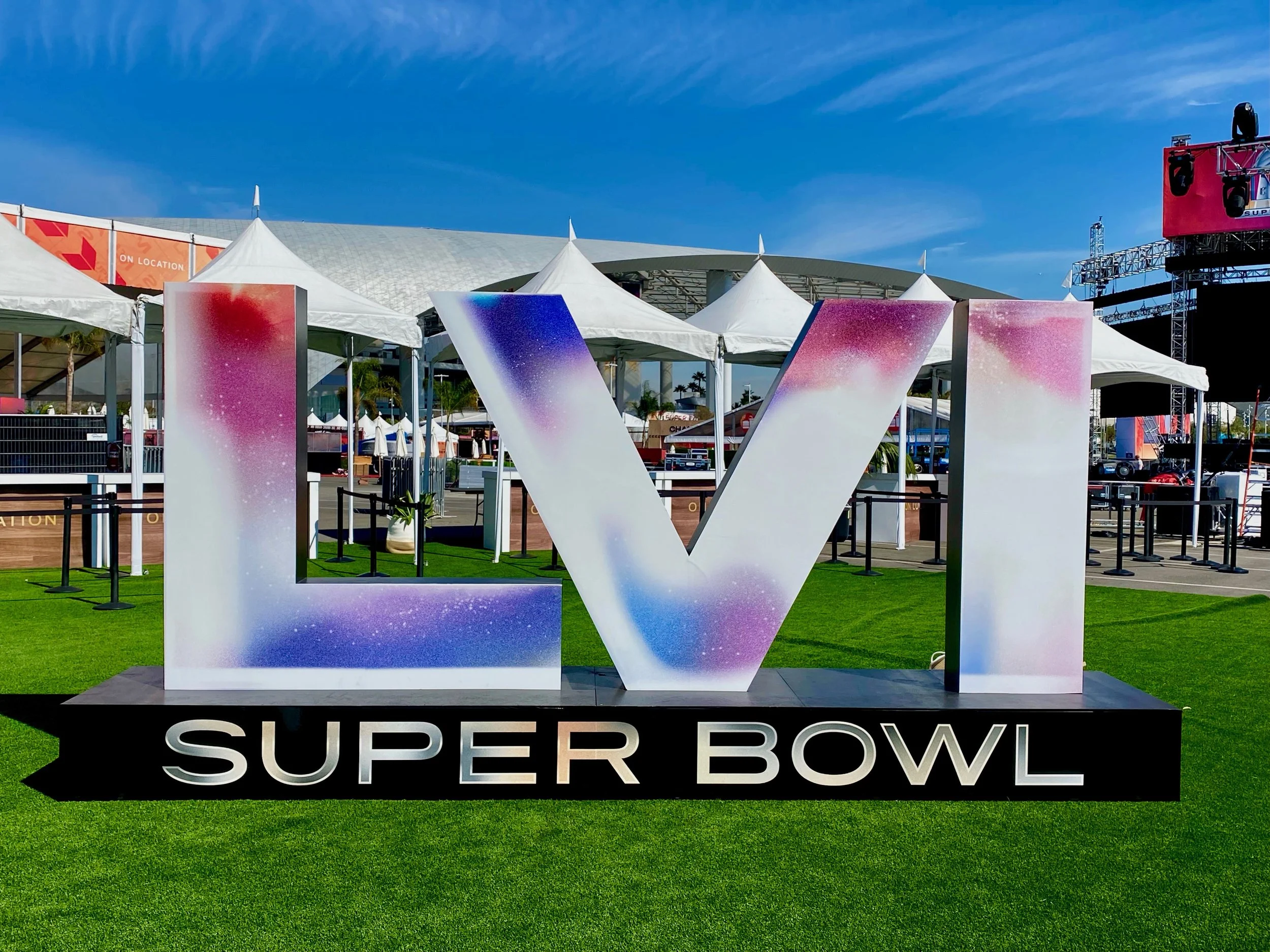 Super Bowl LVI large decorative letter sign on turf with event tents and stadium in background