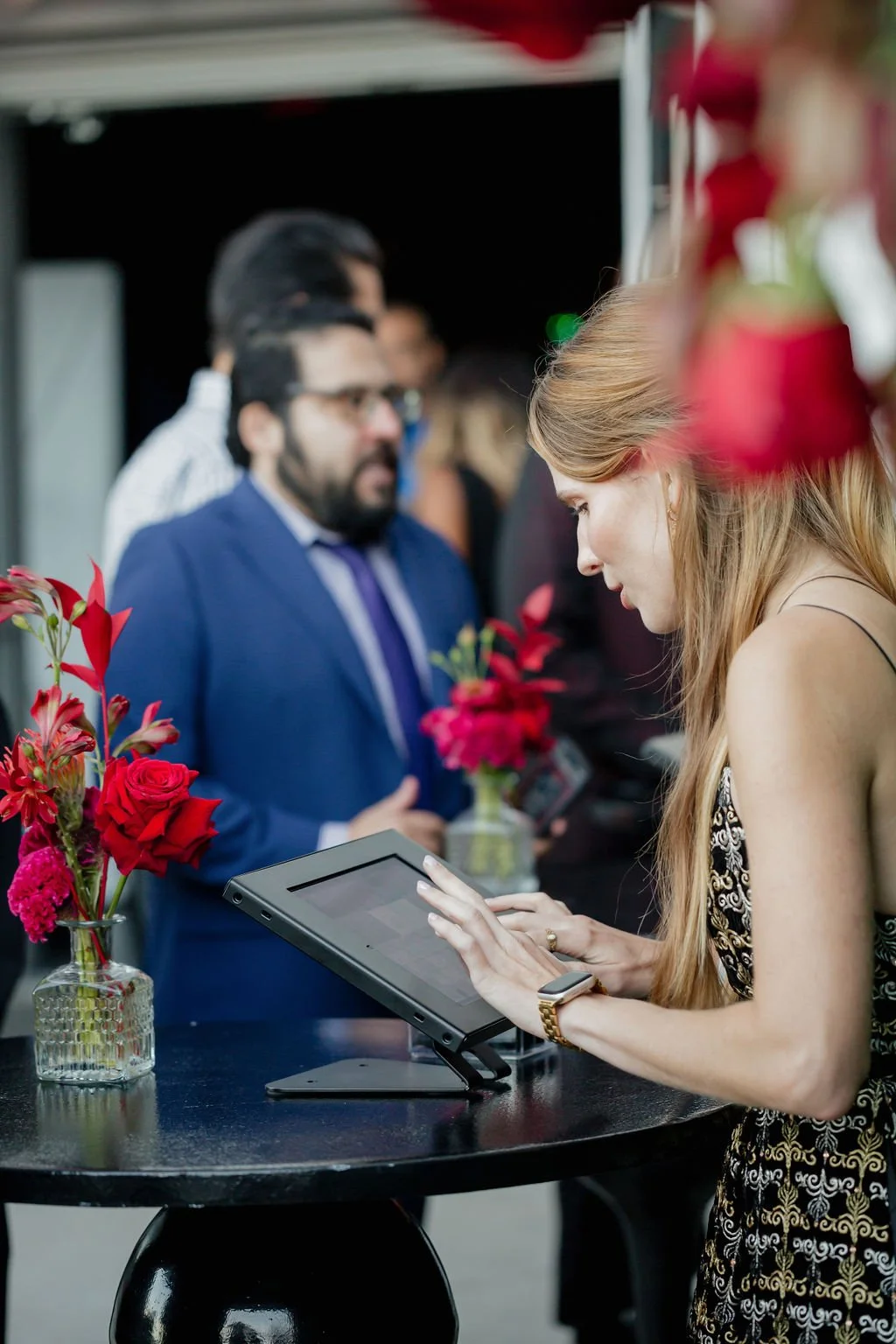 Guest checking in at an Intuit-branded event with red floral arrangements