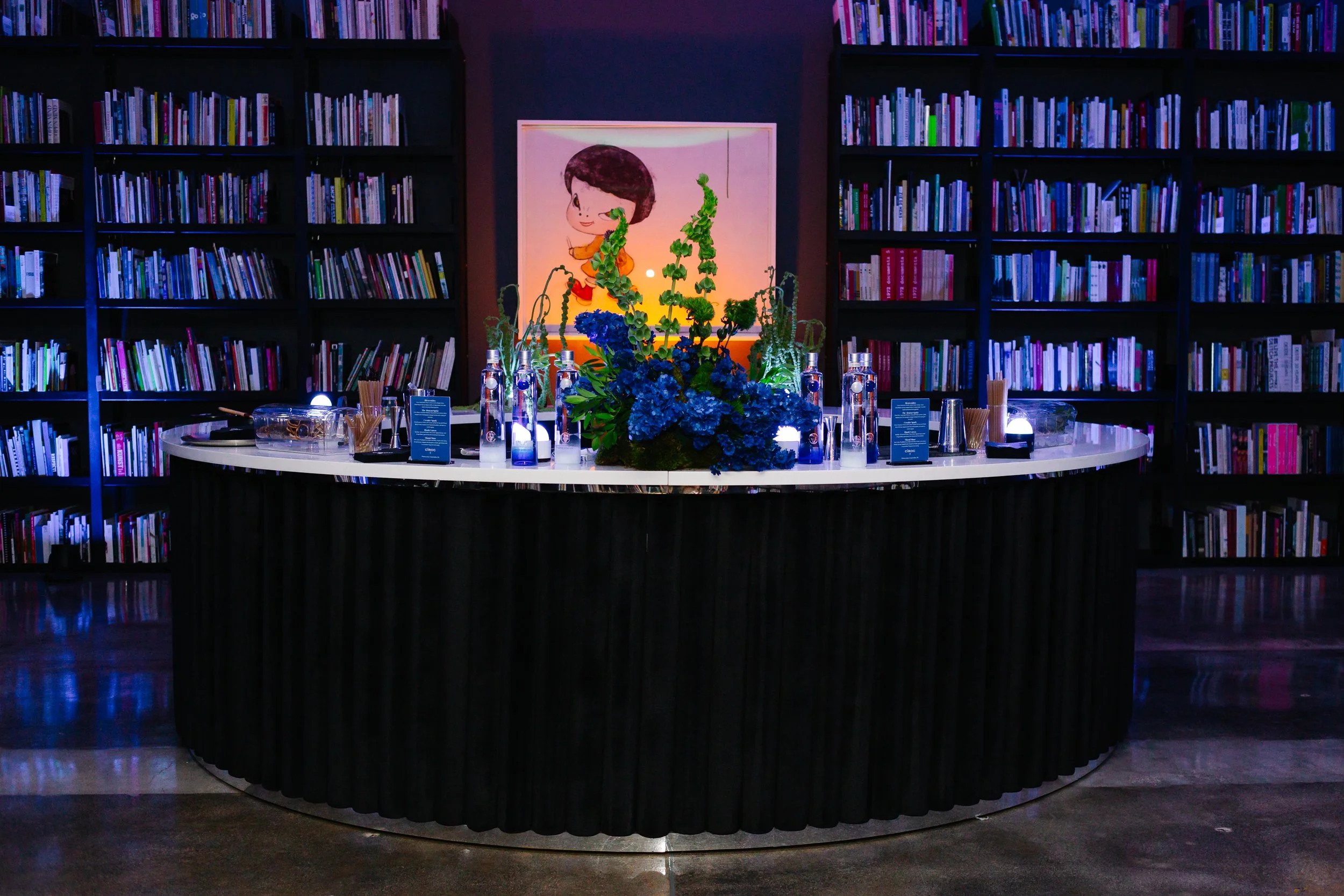 Elegant circular bar with a blue floral centerpiece in a library-style event space