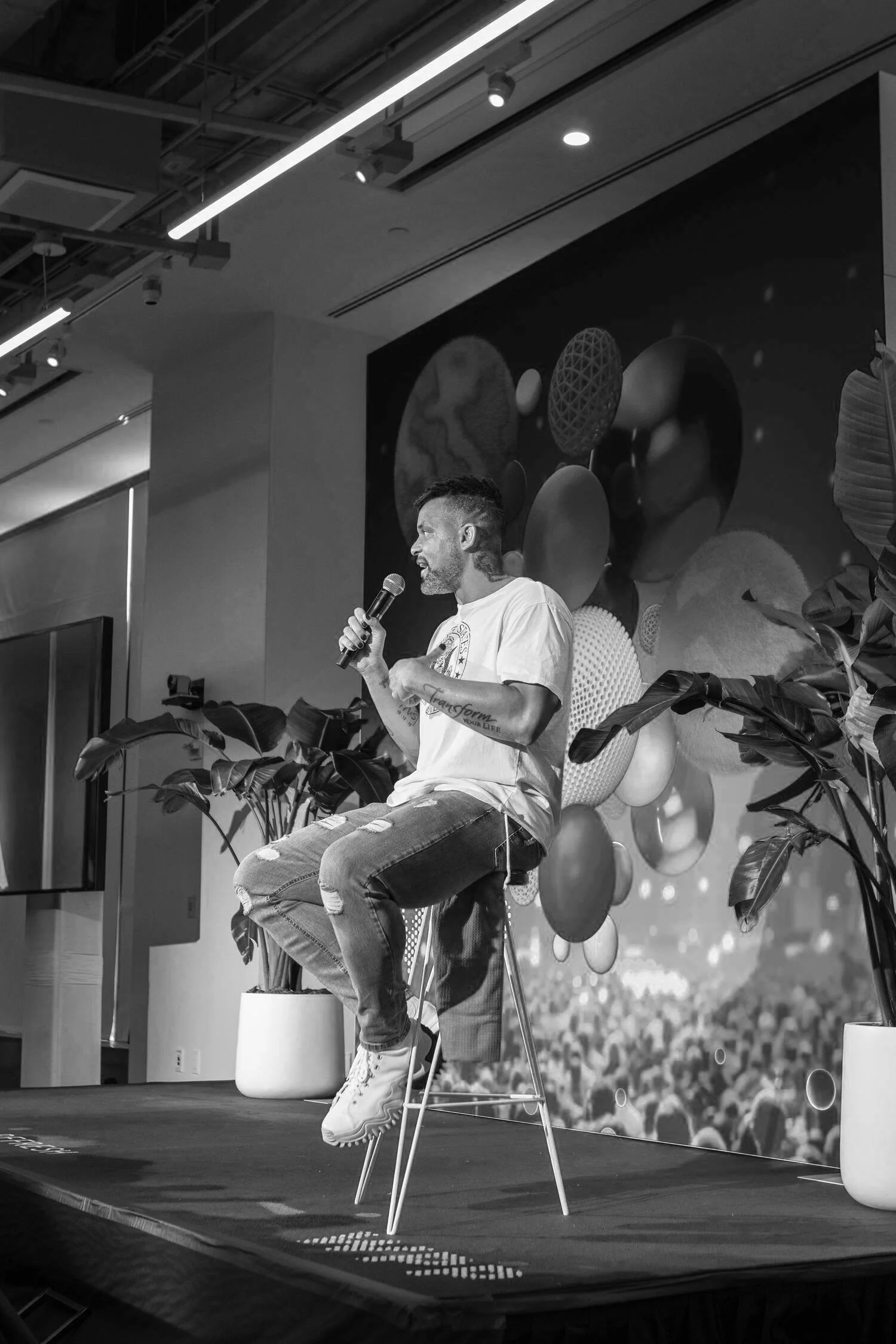 Speaker on stage with a microphone in front of an abstract digital backdrop