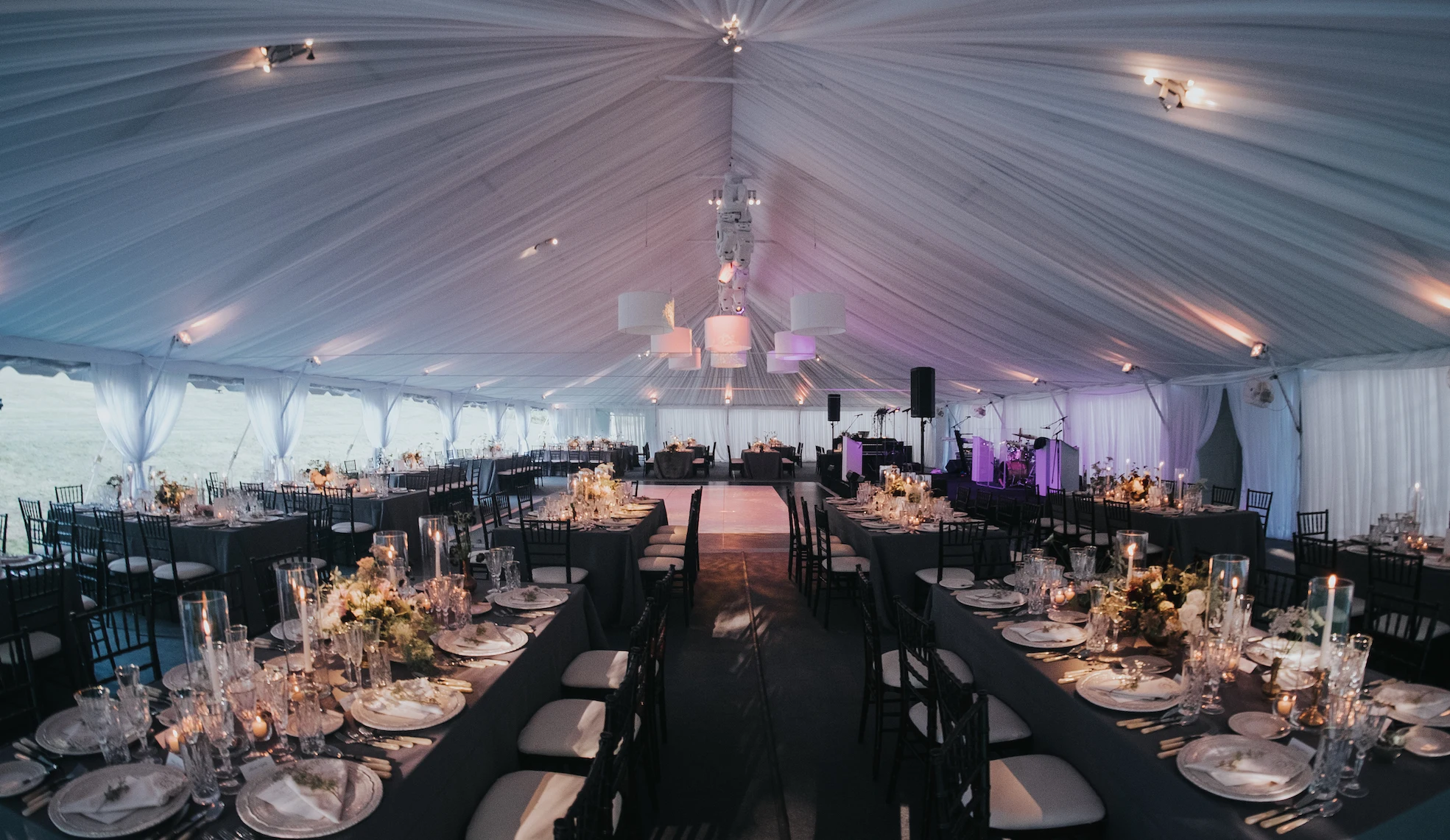 Grand white tent reception interior with dance floor and live band stage
