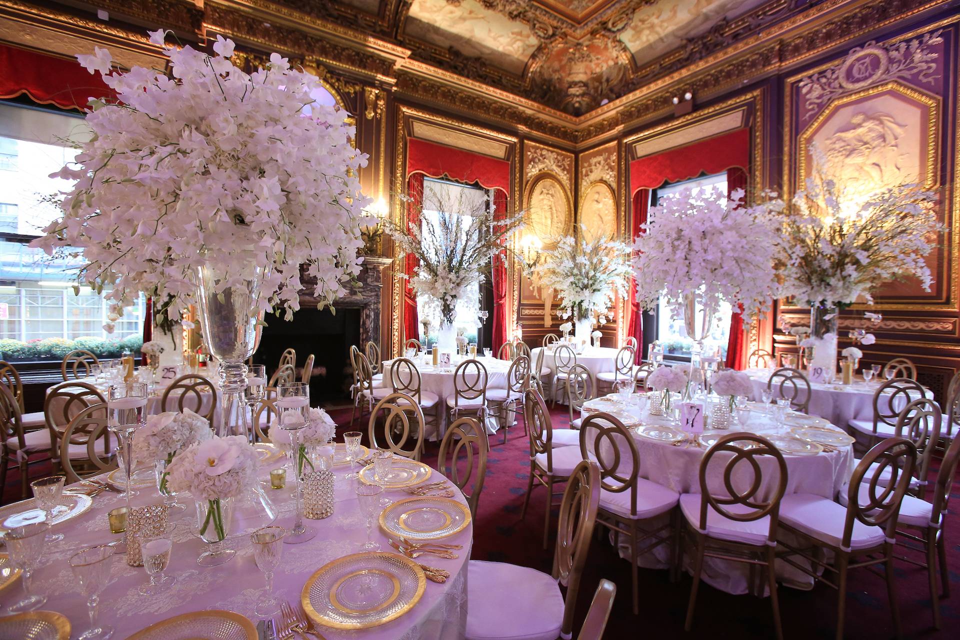 Opulent gilded ballroom reception with tall white orchid centerpieces