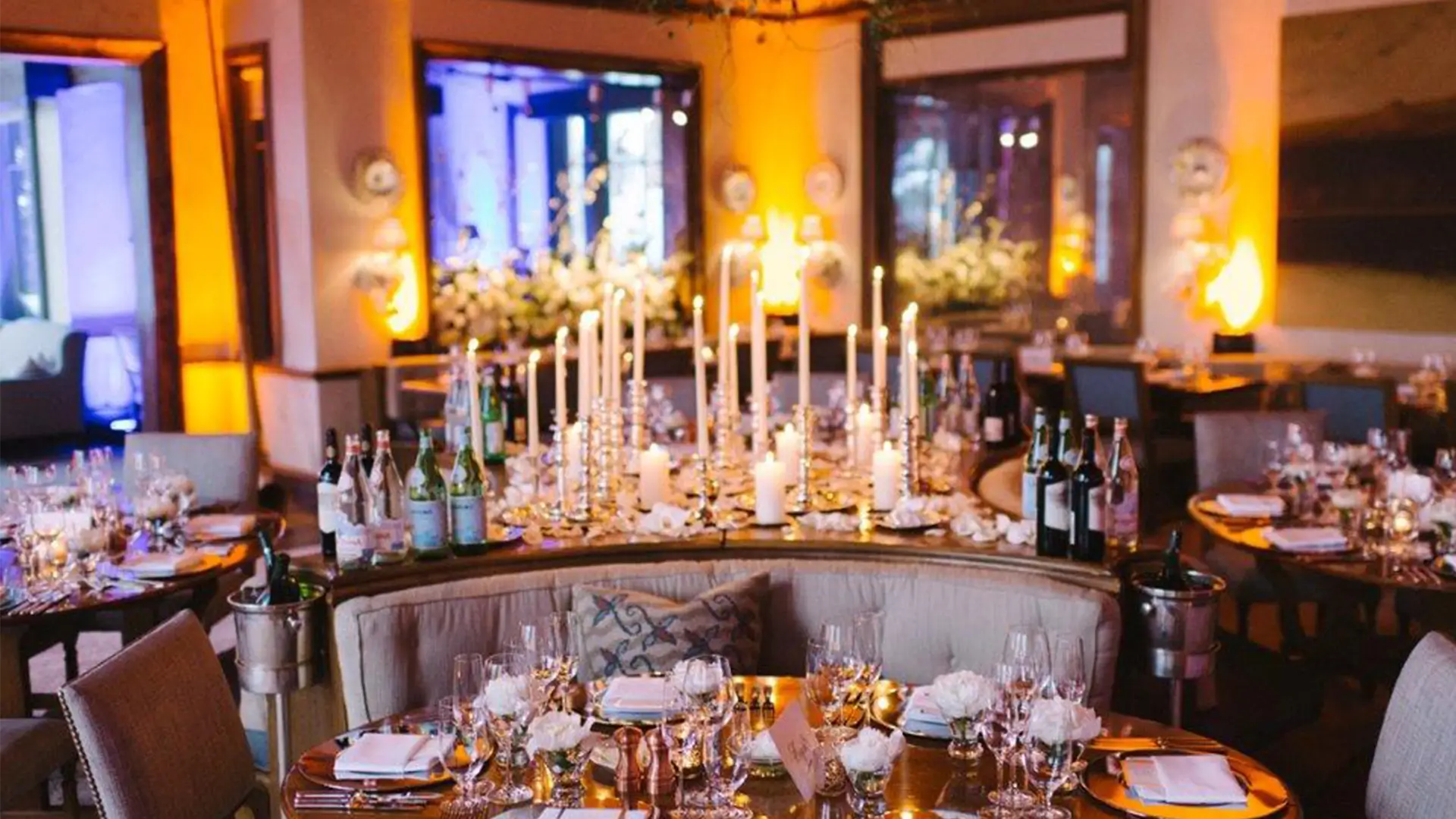 Intimate candlelit dinner in an amber-lit restaurant with tall taper candles