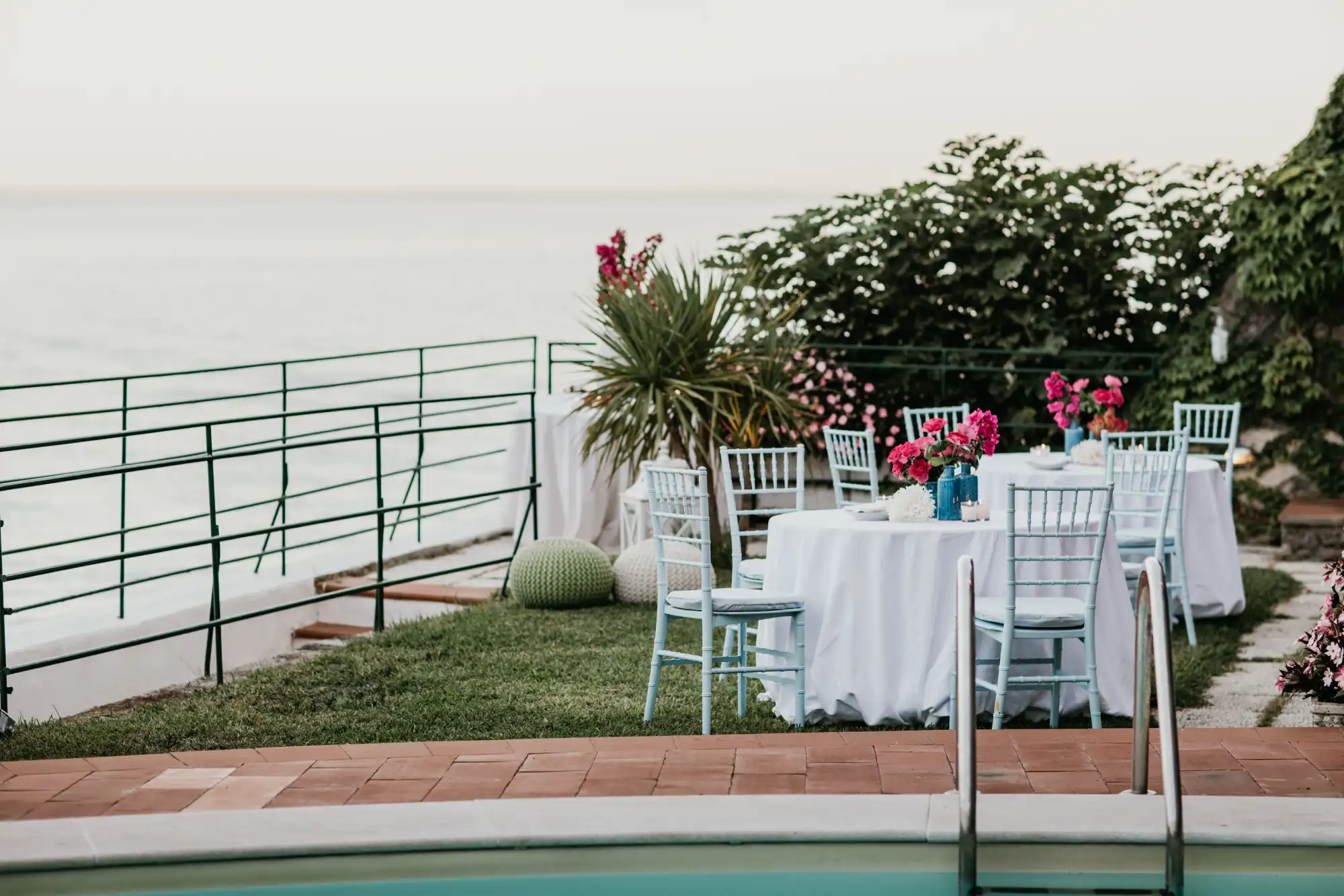Seaside reception table with white linens and pink flowers overlooking the ocean