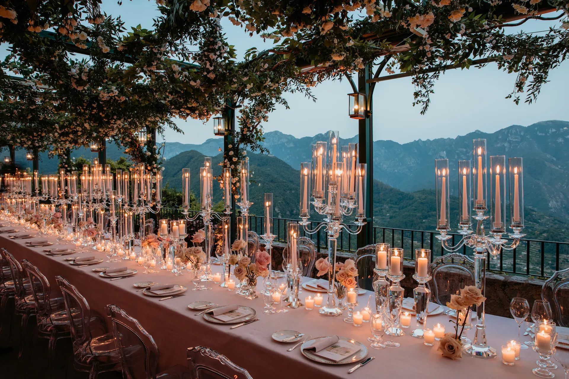 Candlelit outdoor wedding dinner on an Italian terrace overlooking mountains at dusk