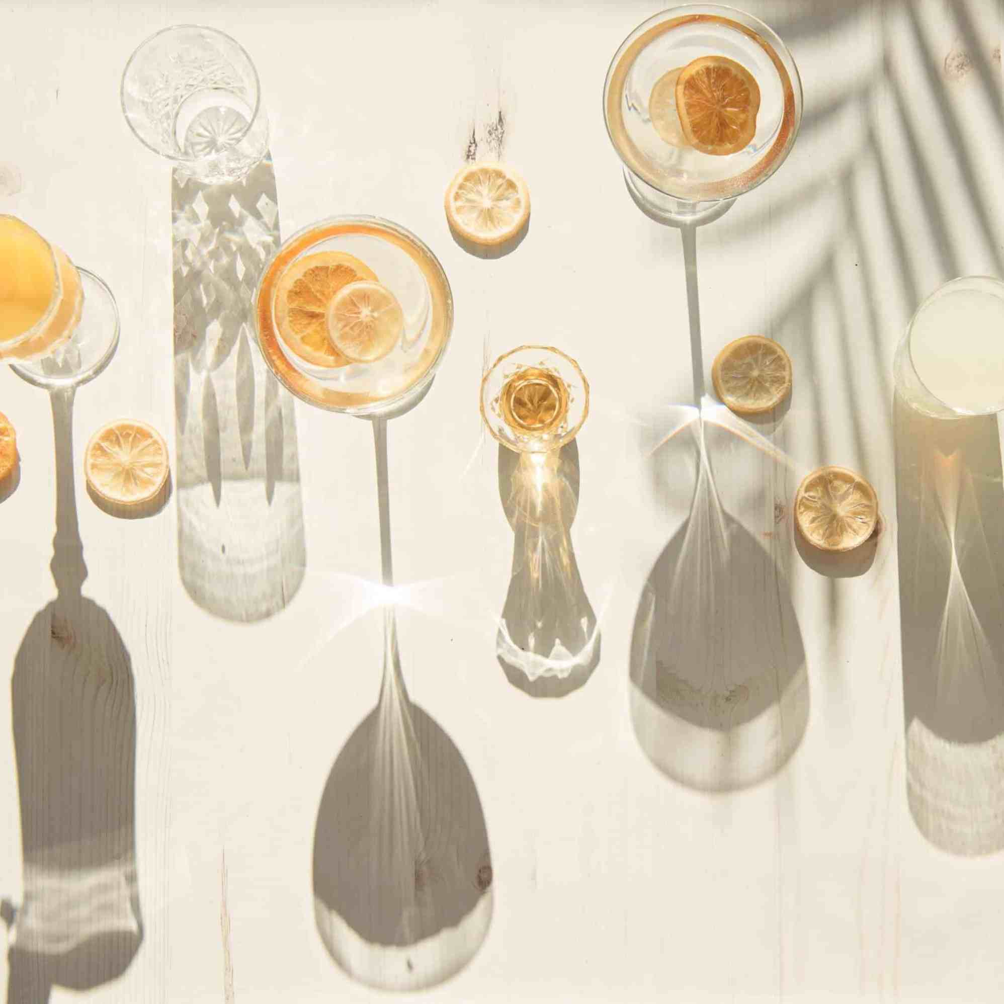 Flat-lay of cocktail glasses with citrus slices casting long shadows