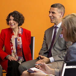 A woman in a red jacket and a man in a suit laughing together in an office