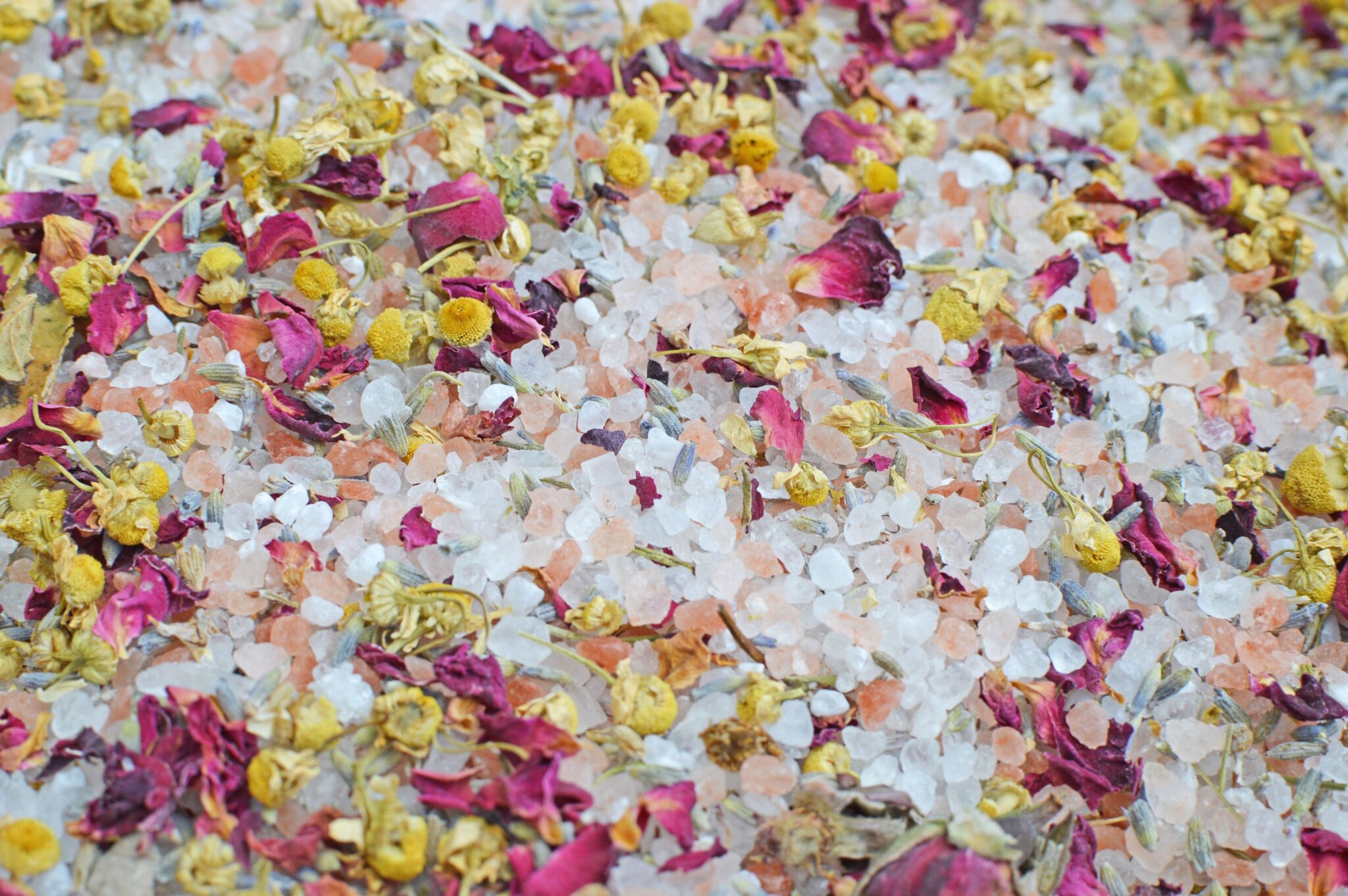 Flat lay of herbal bath salts with rose petals, chamomile and lavender
