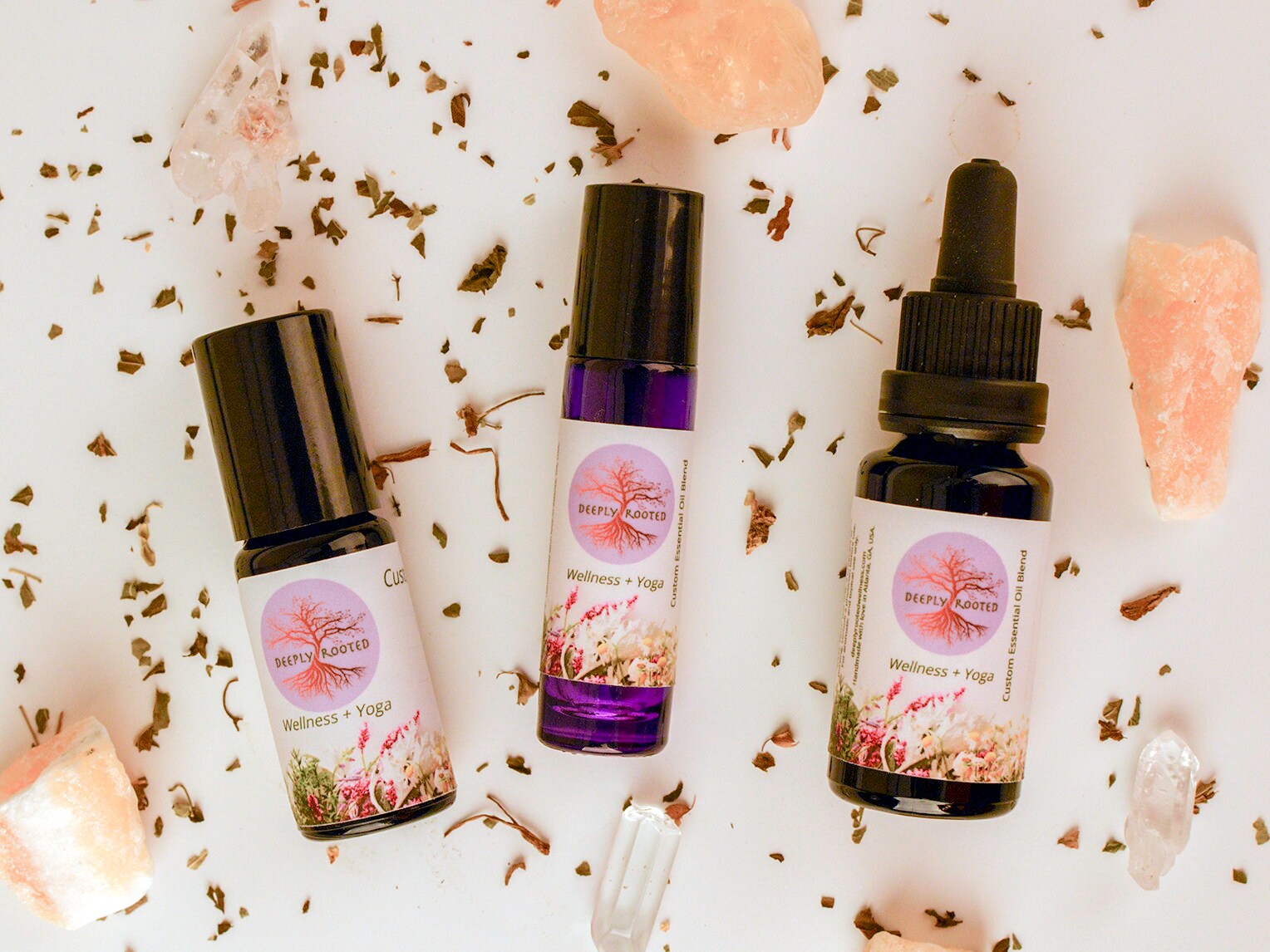 Deeply Rooted branded essential oil bottles with crystals and dried herbs