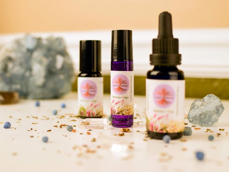 Deeply Rooted essential oil bottles styled with crystals and dried herbs on a shelf