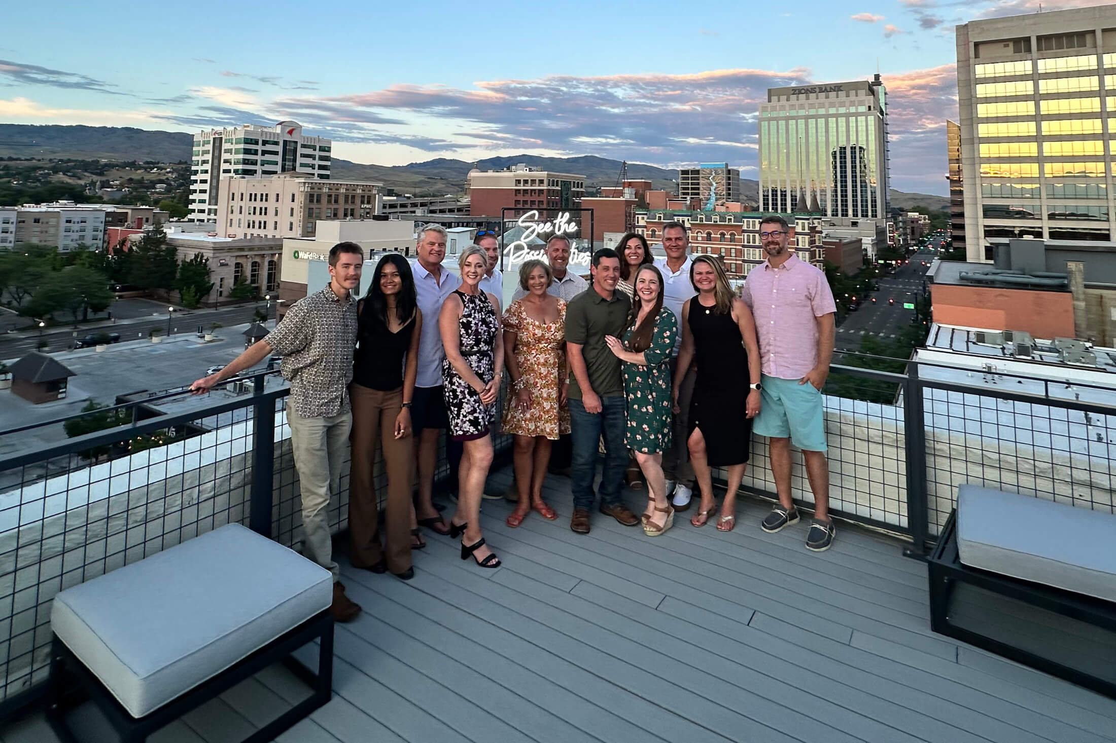 The Deliberate Directions team of about thirteen people on a Boise rooftop terrace at sunset