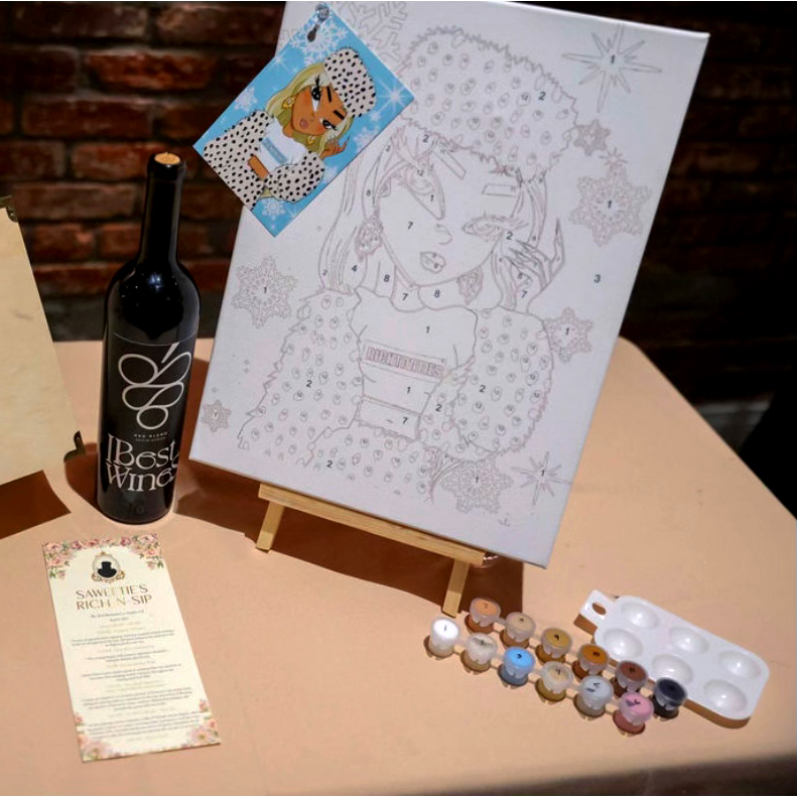 Paint-by-number canvas on a mini easel next to a wine bottle and paint supplies