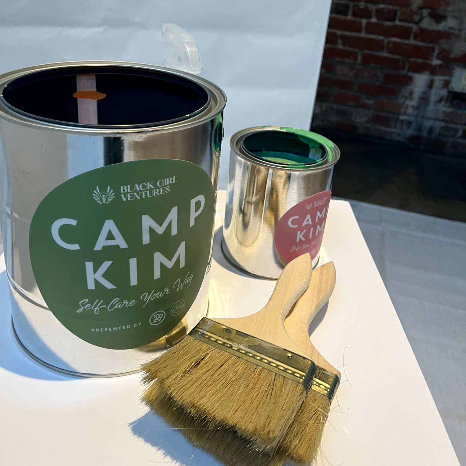 Branded Camp Kim and Black Girl Ventures paint cans with a large paintbrush at a brand activation