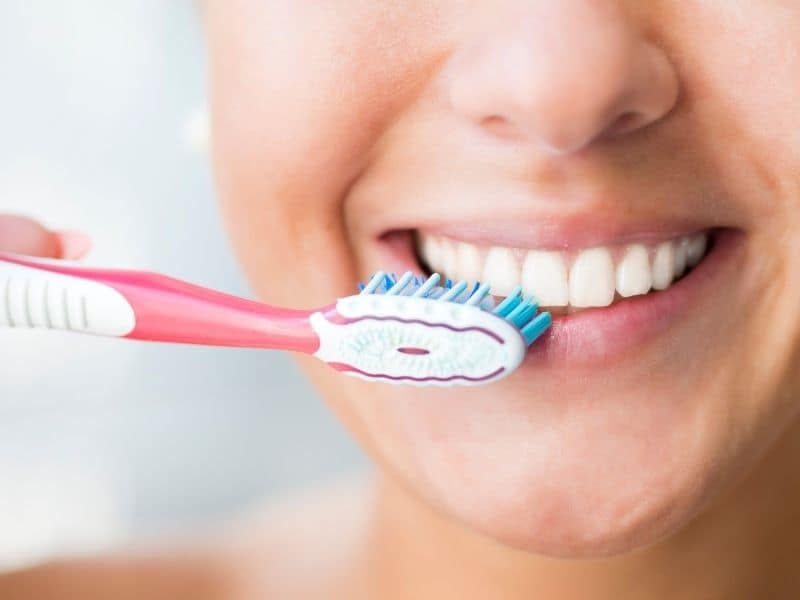 Woman smiling while brushing her teeth